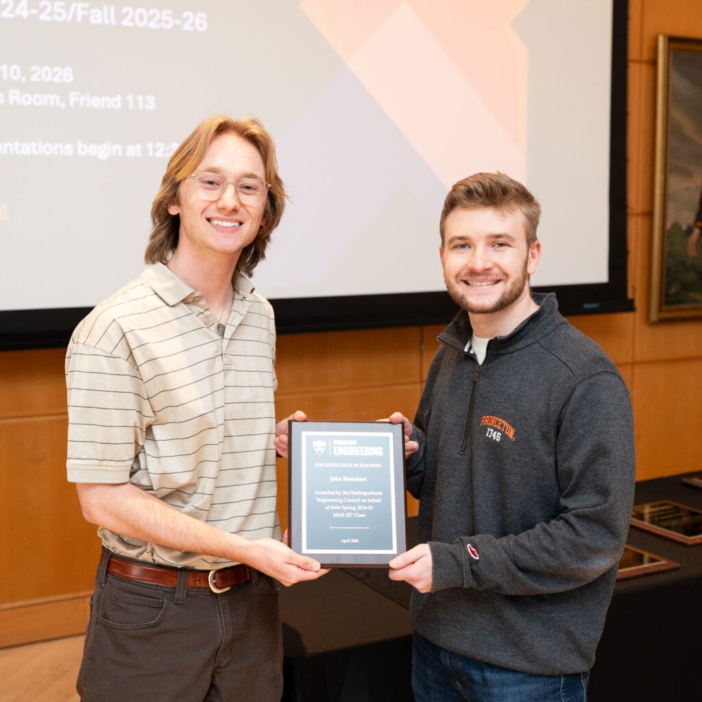 Two men pose together holding an award plaque.
