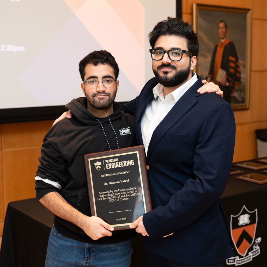 Two men with their arms around each other holding an award plaque.