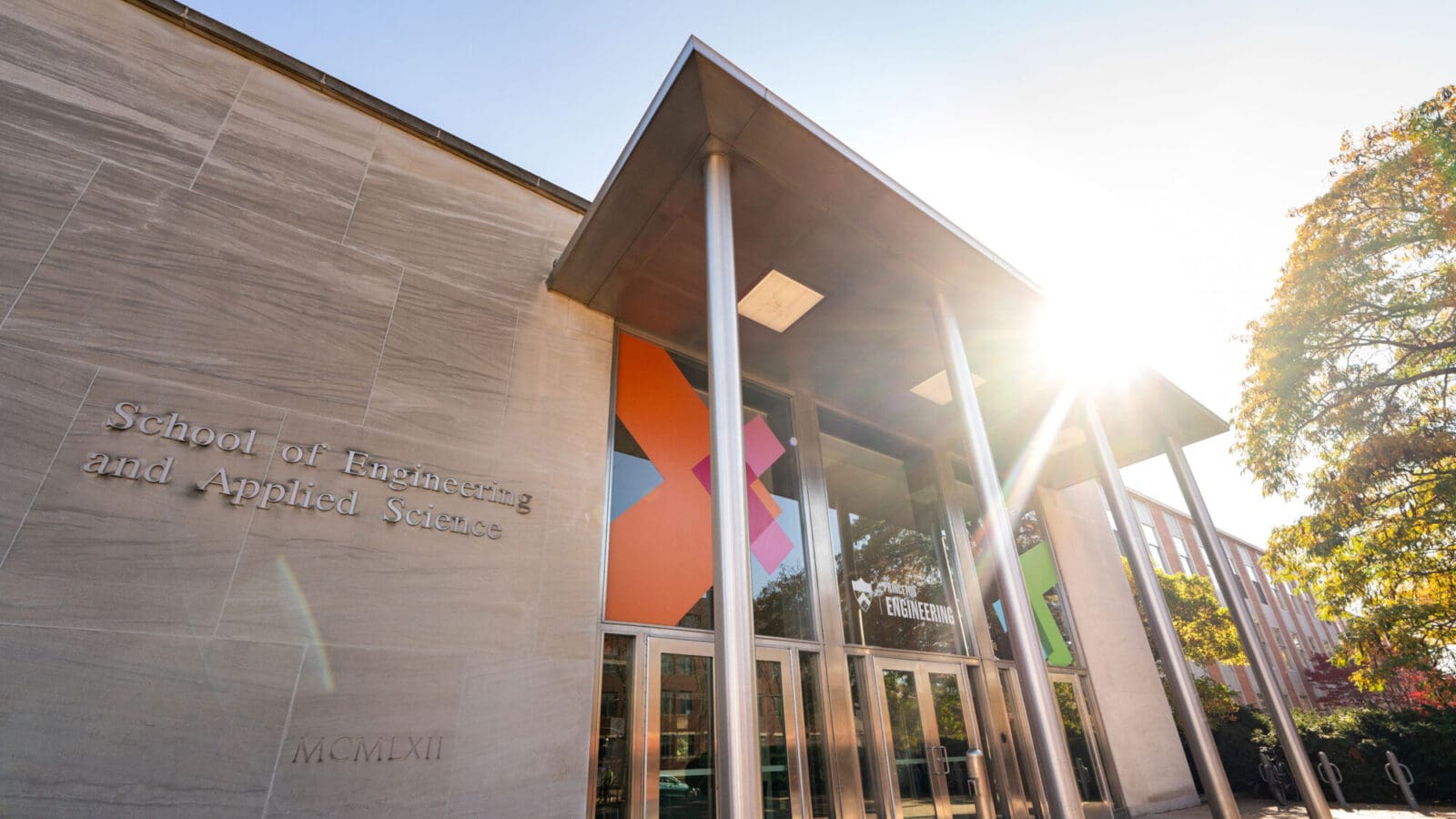 A building facade with large windows and metal columns in front of the entrance.
