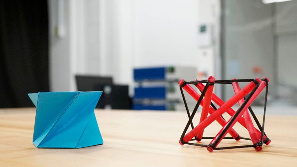 A paper cylinder on a table next to a framework model