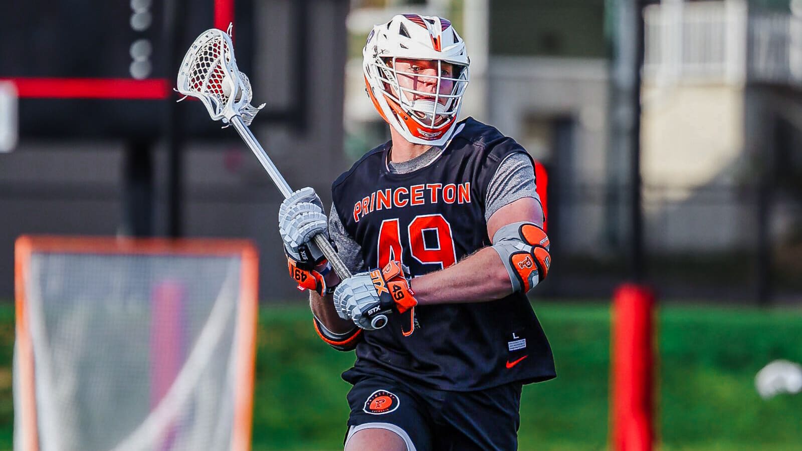 Tyler Harris playing lacrosse, with his stick raised about to throw a ball.