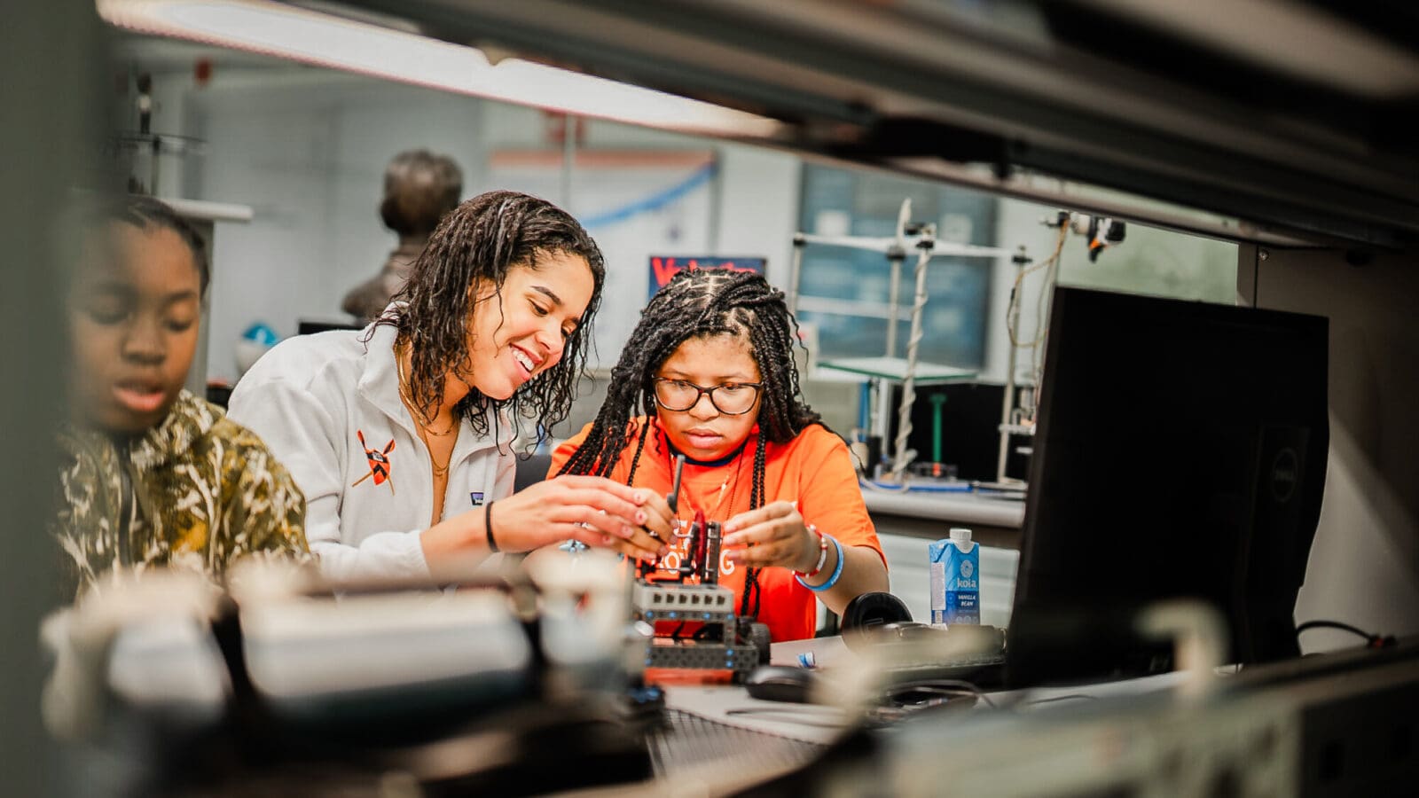 A middle schooler and a college student mentor work together on a robotics project.