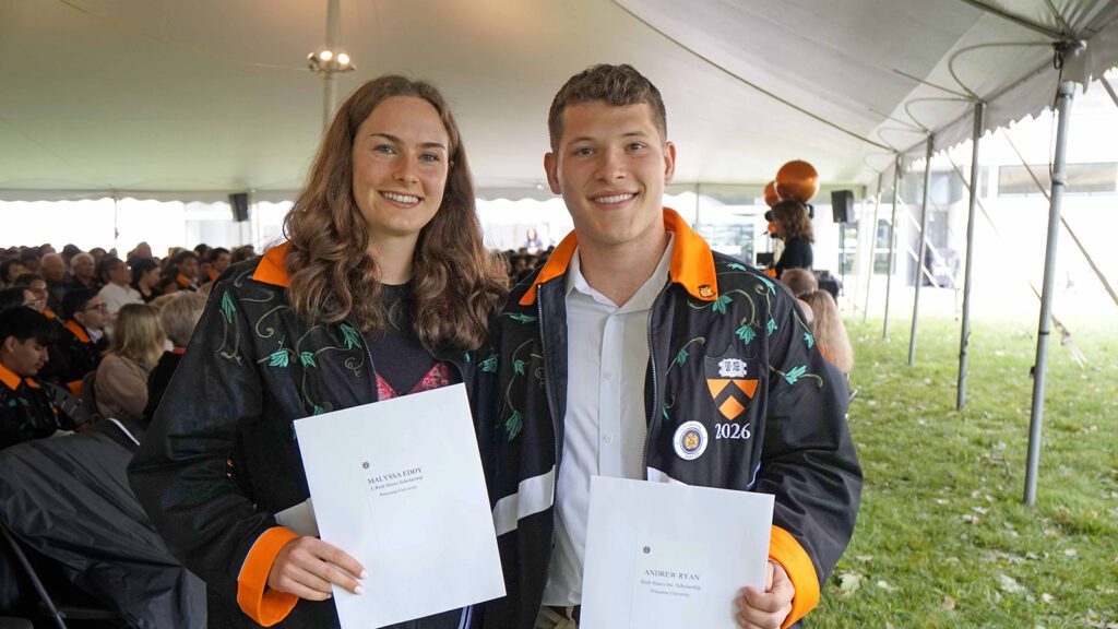 A woman and man hold award citations
