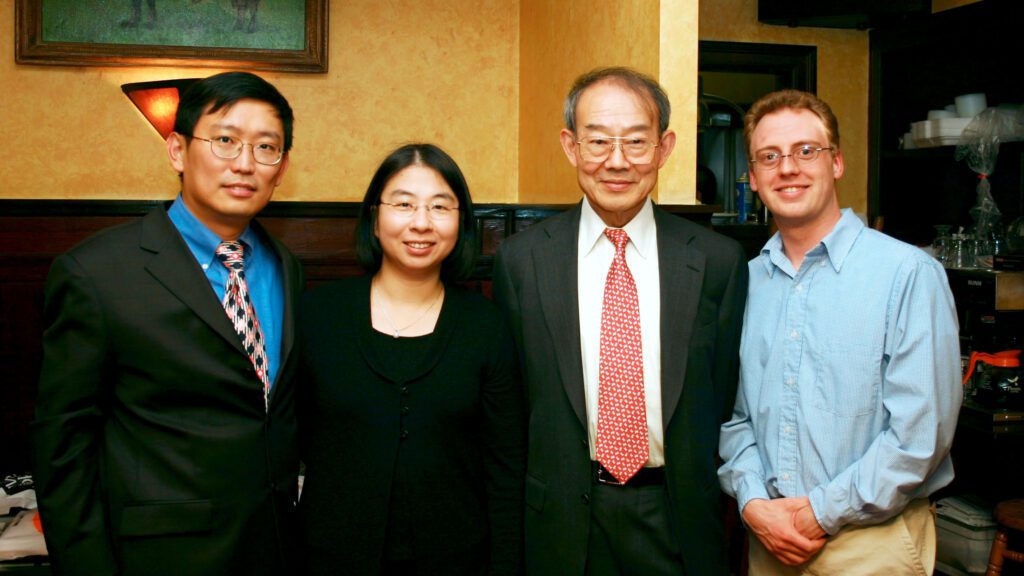 A group of four people in semiformal dress pose for a photo.