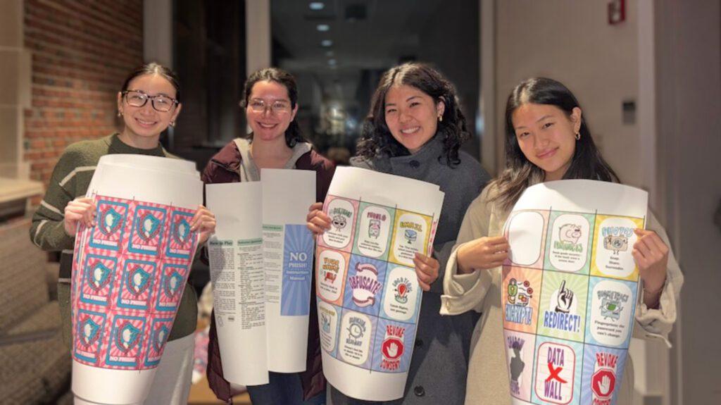 Four students hold posters printed with large cards to be used in a game about data privacy.
