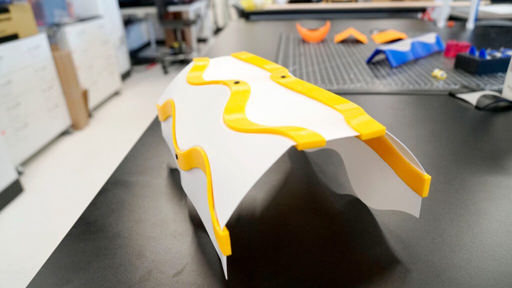 A curved, yellow and white plastic shell sits on a black lab table