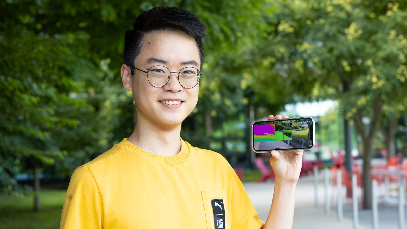 Raymond Liu holding a smartphone displaying an app he created.