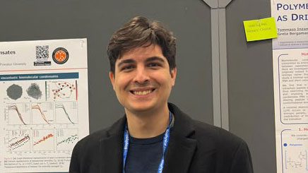 Pablo Garcia standing with a scientific poster at a conference.