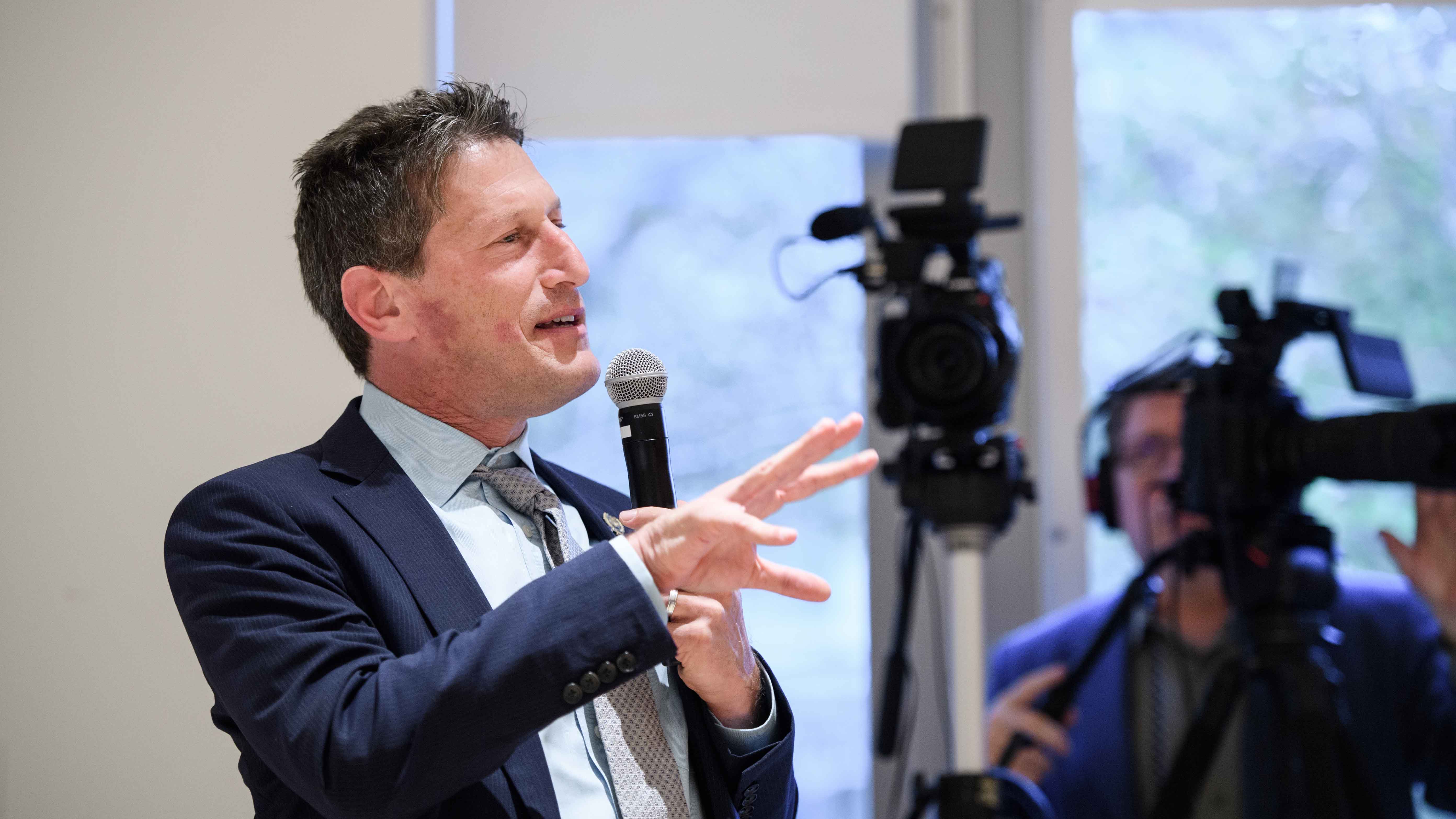 Andrew Zwicker holds microphone.