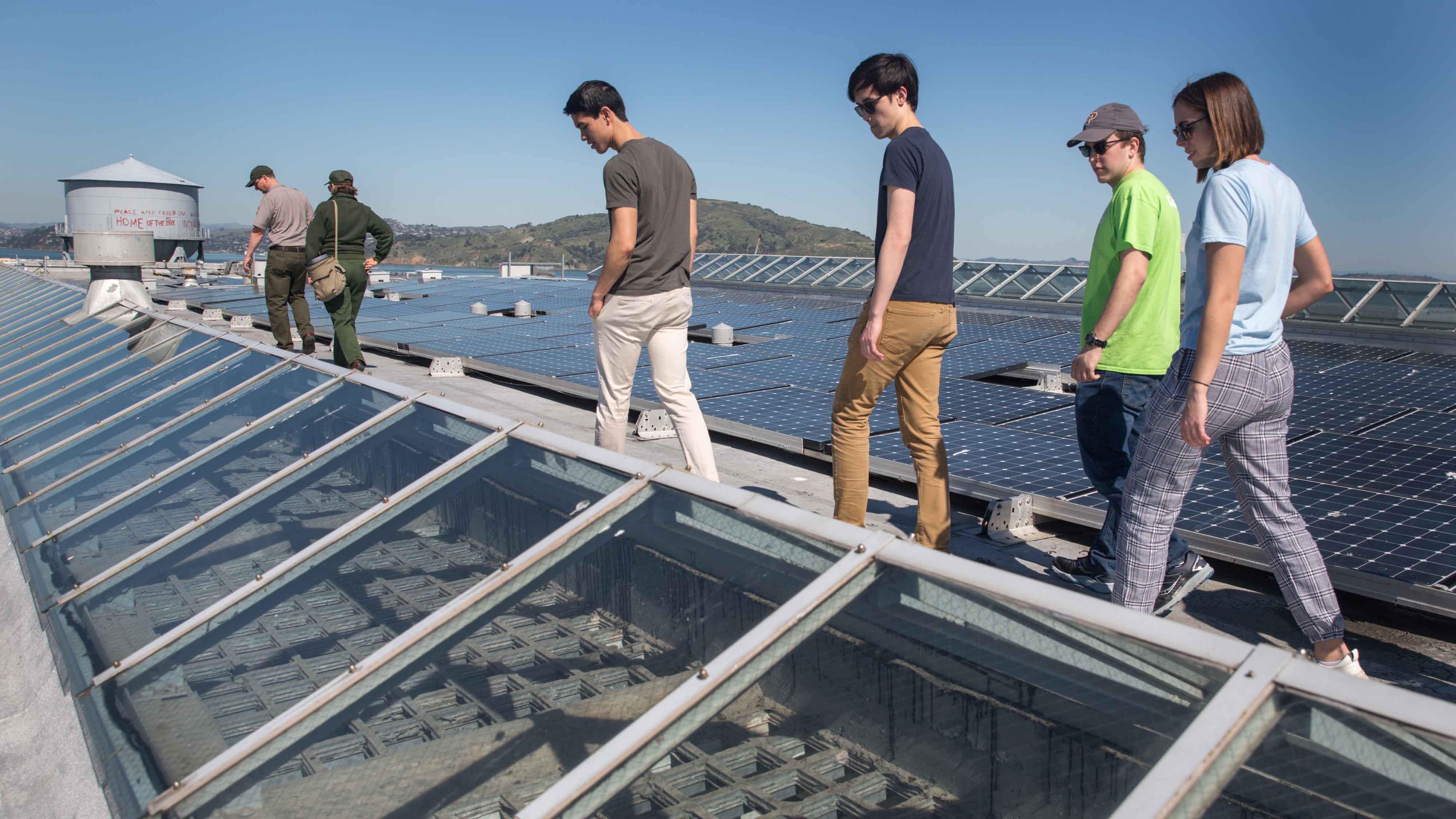 Students pass solar panels on Alcatraz rooftop