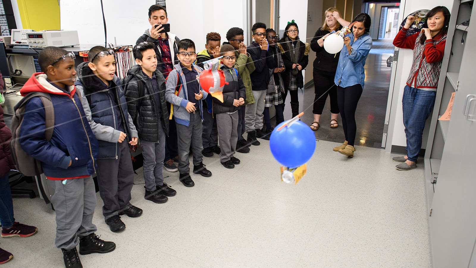 Elementary school students race their balloon-powered rockets along strings