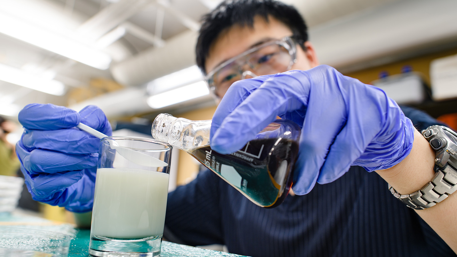 Researcher pours liquids together in lab