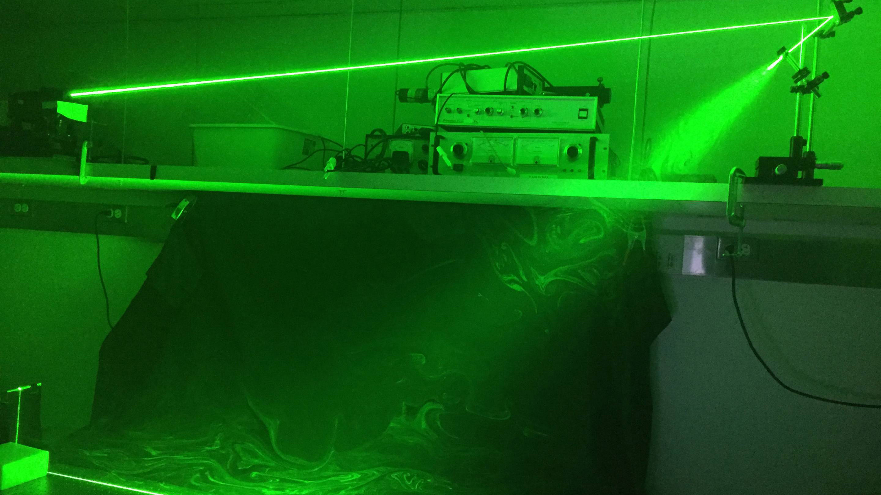 Green laser beam illuminates swirling flow of droplets