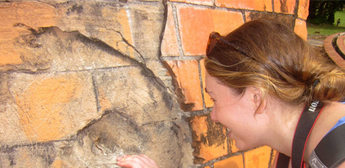 Student looks closely at degraded building wall, in awe
