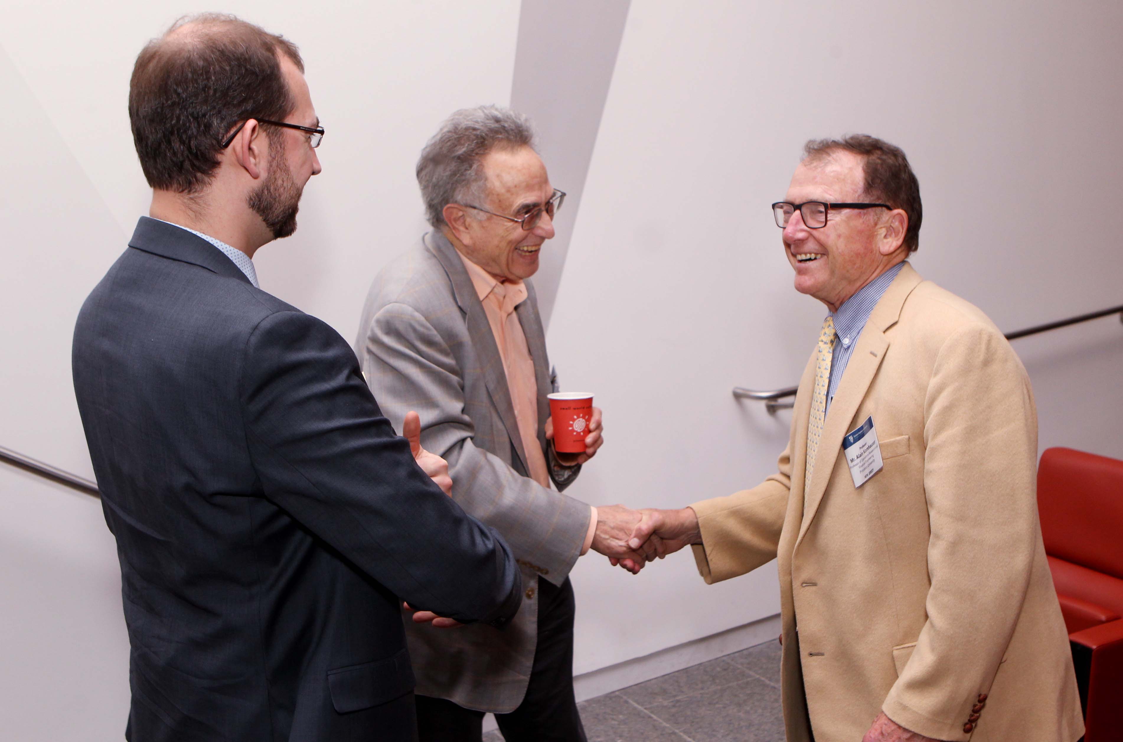 Princeton faculty members Robert Socolow (center), professor of mechanical and aerospace engineering, emeritus, and Alain Kornhauser (right), professor of operations research and financial engineering, shaking hands in this photo, were among the speakers at the event.  Photo byFrank Wojciechowski