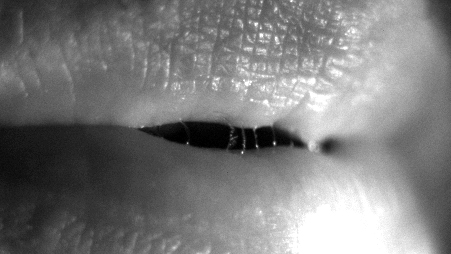 Close-up of lips with filaments of saliva forming