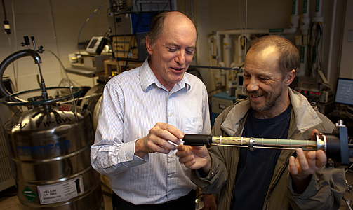 Electrical engineers Stephen Lyon (left) and Alexei Tyryshkin examine the casing            that holds the silicon crystal they used to coordinate the spins of billions of electrons in work toward            developing the technology for powerful machines known as quantum computers. (Photo by John Jameson)