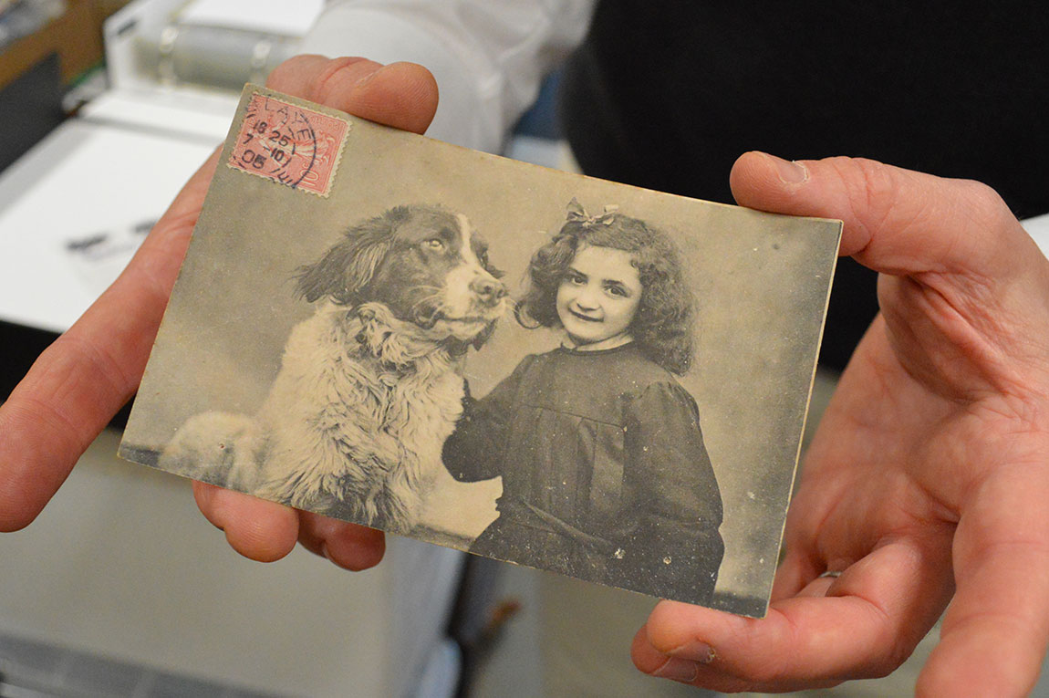 Old black and white postcard being held in a hand